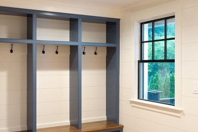 Mid-sized elegant medium tone wood floor and brown floor mudroom photo in Boston with white walls