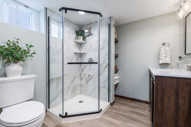 Example of a mid-sized transitional 3/4 multicolored tile and porcelain tile laminate floor, brown floor and single-sink alcove shower design in Minneapolis with brown cabinets, a one-piece toilet, green walls, an undermount sink, quartz countertops, a hinged shower door, white countertops and a freestanding vanity