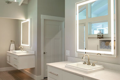 This is an example of a contemporary bathroom in Cincinnati with a drop-in sink, flat-panel cabinets, white cabinets, engineered quartz benchtops, porcelain tile, grey walls, porcelain floors and brown tile.
