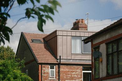 Mittelgroße, Dreistöckige Moderne Doppelhaushälfte mit Metallfassade, roter Fassadenfarbe, Blechdach und rotem Dach in Manchester