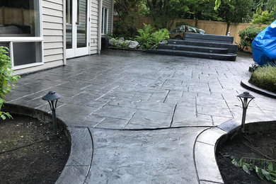 Large traditional backyard patio in Seattle with concrete pavers.