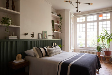 Eclectic bedroom in London with beige walls, light hardwood flooring and beige floors.