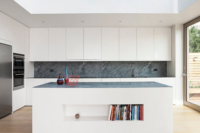 Inspiration for a large modern l-shaped open plan kitchen in London with white cabinets, marble benchtops, grey splashback, stone slab splashback, stainless steel appliances, light hardwood floors, with island, an undermount sink and flat-panel cabinets.