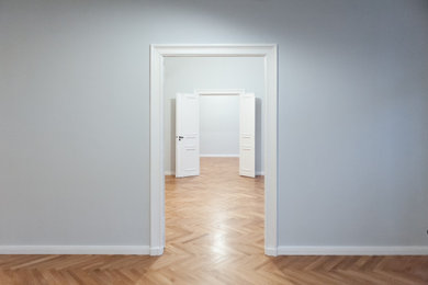 Großes, Offenes Modernes Wohnzimmer mit blauer Wandfarbe, braunem Holzboden und braunem Boden in Berlin