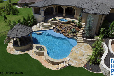 Inspiration for a large rustic backyard stone and custom-shaped natural pool fountain remodel in Oklahoma City