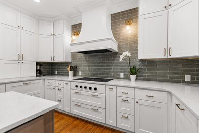 Example of a mid-sized transitional u-shaped medium tone wood floor eat-in kitchen design in Other with white cabinets, quartz countertops, green backsplash, ceramic backsplash, stainless steel appliances, an island and white countertops