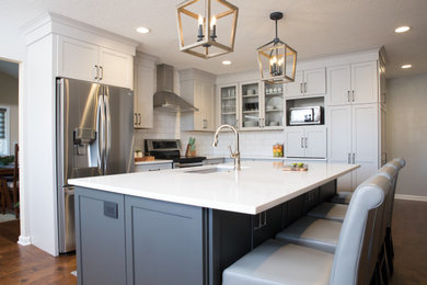 Example of a mid-sized transitional single-wall medium tone wood floor and brown floor eat-in kitchen design in Other with an undermount sink, shaker cabinets, gray cabinets, quartz countertops, white backsplash, subway tile backsplash, stainless steel appliances, an island and white countertops
