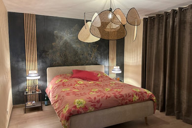Imagen de dormitorio gris y negro tropical de tamaño medio sin chimenea con paredes beige, suelo laminado, suelo beige y madera