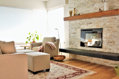 This is an example of a mid-sized contemporary open concept living room in Vancouver with beige walls, a stone fireplace surround and brown floor.