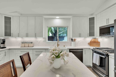 Example of a large transitional u-shaped porcelain tile, brown floor and vaulted ceiling eat-in kitchen design with an undermount sink, shaker cabinets, white cabinets, multicolored backsplash, quartz backsplash, stainless steel appliances, an island, multicolored countertops and quartzite countertops