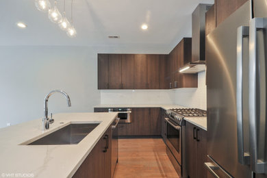 Minimalist l-shaped open concept kitchen photo in Chicago with flat-panel cabinets, dark wood cabinets, an island, white countertops and stainless steel appliances