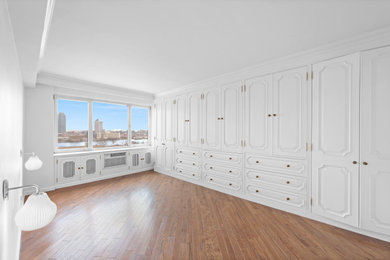 Imagen de dormitorio principal grande con paredes blancas, suelo de madera en tonos medios y suelo marrón