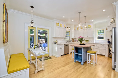 Photo of a mid-sized traditional u-shaped eat-in kitchen in San Diego with an undermount sink, recessed-panel cabinets, white cabinets, wood benchtops, white splashback, ceramic splashback, stainless steel appliances, light hardwood floors and with island.