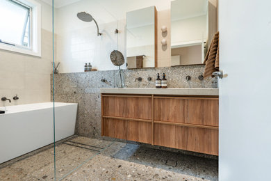 Inspiration for a mid-sized contemporary wet room bathroom in Sydney with flat-panel cabinets, medium wood cabinets, a corner tub, a two-piece toilet, beige tile, porcelain tile, white walls, terrazzo floors, an undermount sink, grey floor, an open shower, beige benchtops, an enclosed toilet, a double vanity and a floating vanity.