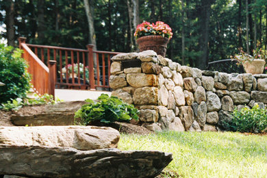 This is an example of a traditional backyard partial sun garden for summer in New York with a retaining wall.