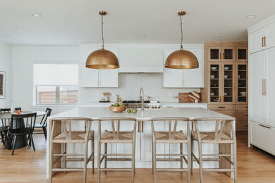 Inspiration for a transitional l-shaped medium tone wood floor and brown floor eat-in kitchen remodel in Denver with shaker cabinets, white cabinets, white backsplash, paneled appliances, an island and white countertops