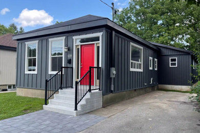 Example of a huge minimalist black one-story concrete fiberboard and board and batten house exterior design in Toronto with a black roof