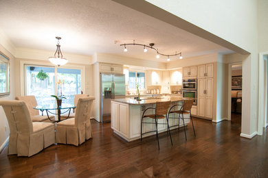 Inspiration for a mid-sized timeless l-shaped dark wood floor and brown floor eat-in kitchen remodel in Other with raised-panel cabinets, beige cabinets, granite countertops, stainless steel appliances and an island
