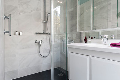 Photo of a mid-sized contemporary master bathroom in Paris with a curbless shower, white tile, blue tile, white walls, grey floor, a hinged shower door, white benchtops and white cabinets.