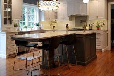 Inspiration for a mid-sized transitional l-shaped kitchen in Philadelphia with an undermount sink, beaded inset cabinets, white cabinets, quartz benchtops, white splashback, subway tile splashback, stainless steel appliances, medium hardwood floors, with island, brown floor and white benchtop.