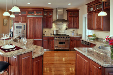 Inspiration for a mid-sized timeless l-shaped light wood floor and beige floor eat-in kitchen remodel in Other with an undermount sink, raised-panel cabinets, medium tone wood cabinets, granite countertops, beige backsplash, porcelain backsplash, stainless steel appliances and an island