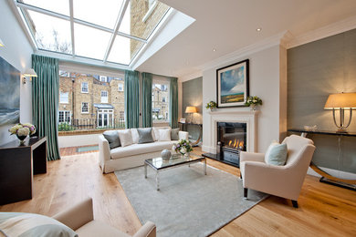 Living room - mid-sized transitional enclosed light wood floor and beige floor living room idea in London with gray walls and a standard fireplace