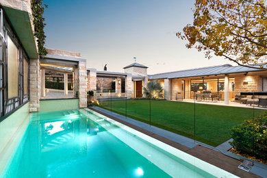 Photo of a large contemporary front yard custom-shaped pool in Sydney with natural stone pavers.