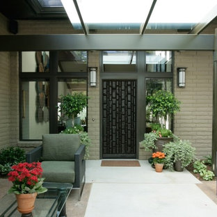 Idéer för en liten eklektisk ingång och ytterdörr, med beige väggar, betonggolv, en enkeldörr och en svart dörr