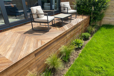 Inspiration for a contemporary back xeriscape full sun garden in Sussex with decking and a wood fence.