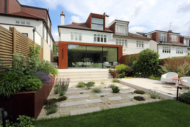 Photo of a large modern back formal partial sun garden for summer in London with a living wall, decking and a wood fence.