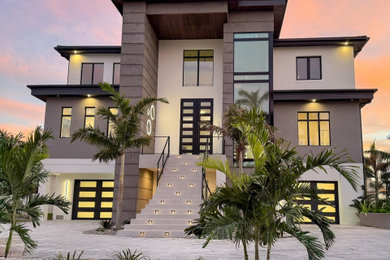 Inspiration for a beige three-story exterior home remodel in Miami with a brown roof