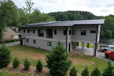Modern two-story stucco house exterior idea with a shed roof, a metal roof and a black roof