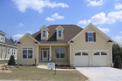 Mid-sized elegant yellow two-story vinyl house exterior photo in Other with a hip roof and a shingle roof