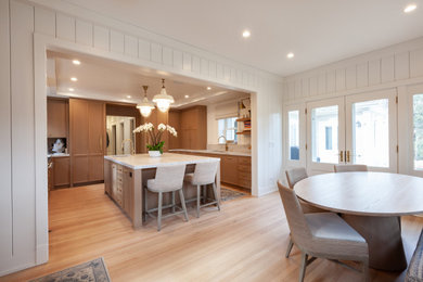Large coastal u-shaped kitchen/diner in Chicago with a submerged sink, shaker cabinets, medium wood cabinets, integrated appliances, an island, beige floors and a timber clad ceiling.