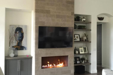 Inspiration for a mid-sized modern enclosed porcelain tile living room remodel in Phoenix with white walls, a ribbon fireplace, a stone fireplace and a wall-mounted tv