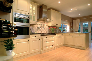 Design ideas for a large traditional l-shaped kitchen in Other with stainless steel appliances, light hardwood flooring and a breakfast bar.