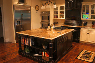 Inspiration for a medium tone wood floor kitchen remodel in Other with raised-panel cabinets, yellow cabinets, granite countertops, beige backsplash, stainless steel appliances and an island