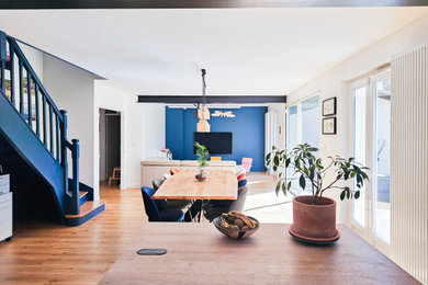 Exemple d'une très grande salle à manger ouverte sur la cuisine avec un mur bleu, parquet clair, aucune cheminée et un sol marron.