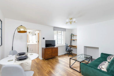 Kleines, Offenes Modernes Wohnzimmer mit weißer Wandfarbe, hellem Holzboden, Kamin, verputzter Kaminumrandung und braunem Boden in Sussex