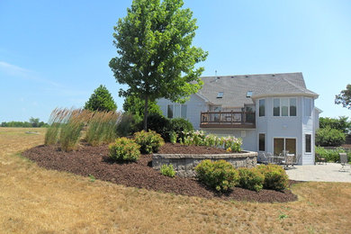 Inspiration for a mid-sized traditional full sun backyard stone retaining wall landscape in Milwaukee.