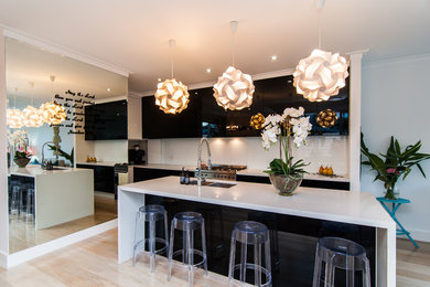 Inspiration for a mid-sized contemporary galley open plan kitchen in Brisbane with white splashback, stainless steel appliances, light hardwood floors, with island, multi-coloured benchtop, a drop-in sink, flat-panel cabinets, black cabinets, quartz benchtops, cement tile splashback and brown floor.