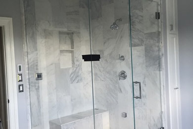 This is an example of a transitional bathroom in New York with a corner shower, gray tile, white tile, stone tile, grey walls and marble floors.