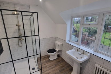 This is an example of a large traditional ensuite bathroom in West Midlands with a walk-in shower, a two-piece toilet, white tiles, ceramic tiles, white walls, vinyl flooring, a pedestal sink, multi-coloured floors, an open shower and a wall niche.
