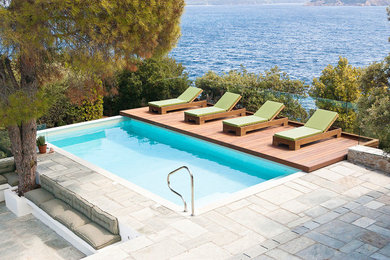 Photo of a medium sized contemporary back rectangular lengths swimming pool in London with natural stone paving.