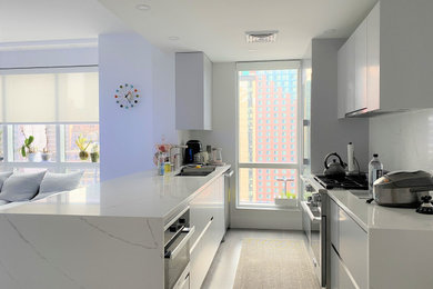 Eat-in kitchen - mid-sized modern galley dark wood floor and brown floor eat-in kitchen idea in New York with an undermount sink, flat-panel cabinets, gray cabinets, quartz countertops, white backsplash, quartz backsplash, stainless steel appliances, an island and white countertops