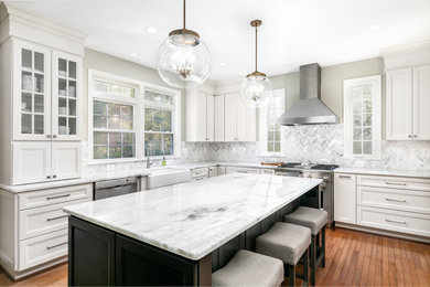 Inspiration for a large transitional u-shaped eat-in kitchen in DC Metro with a farmhouse sink, recessed-panel cabinets, white cabinets, quartzite benchtops, white splashback, glass sheet splashback, stainless steel appliances, medium hardwood floors, with island, brown floor and white benchtop.