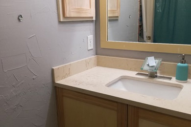 Diseño de cuarto de baño actual con armarios estilo shaker, puertas de armario de madera clara, lavabo bajoencimera y encimera de cuarzo compacto