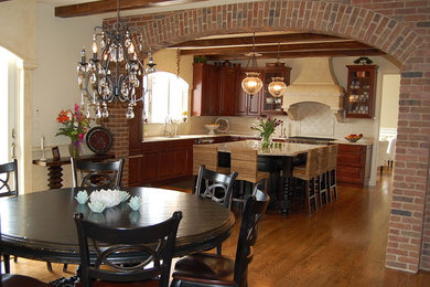 Mid-sized tuscan l-shaped medium tone wood floor and brown floor enclosed kitchen photo in New York with a double-bowl sink, raised-panel cabinets, medium tone wood cabinets, granite countertops, white backsplash, subway tile backsplash, stainless steel appliances and an island
