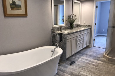 Small trendy 3/4 ceramic tile and gray floor freestanding bathtub photo in Denver with recessed-panel cabinets, distressed cabinets, a one-piece toilet, gray walls, an undermount sink, granite countertops and a hinged shower door