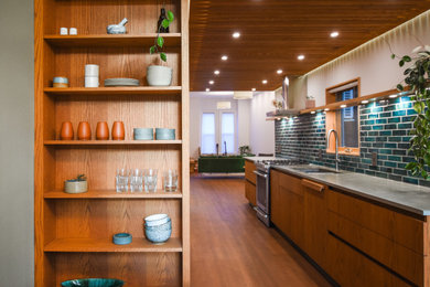 This is an example of a medium sized midcentury single-wall kitchen/diner in Toronto with a submerged sink, flat-panel cabinets, medium wood cabinets, concrete worktops, blue splashback, metro tiled splashback, stainless steel appliances, medium hardwood flooring, no island, brown floors, grey worktops and a wood ceiling.